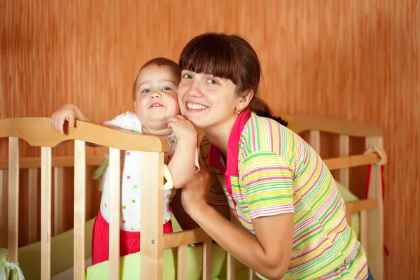 Happy mother with baby in crib