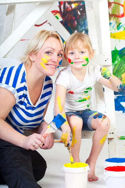 Girl in a white T-shirt with mum, bedaubed with bright paints