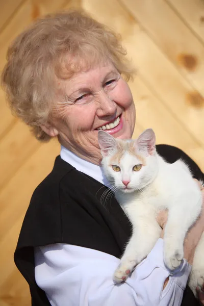 Smiling aged woman with cat on hands