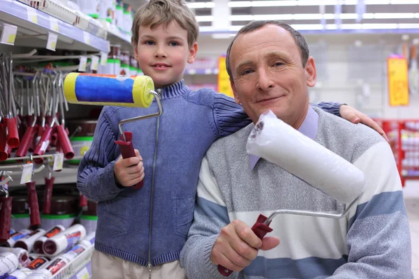 Elderly man with boy in shop with painting rollers in hands