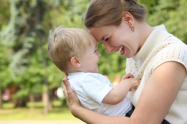 Mother hold baby on hands outdoor in summer and looks on each ot