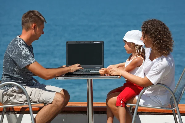 Family resting on sea with laptop