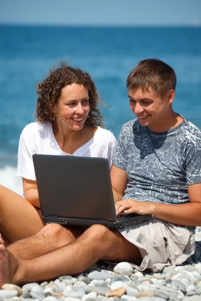 Man and girl on seashore with laptop