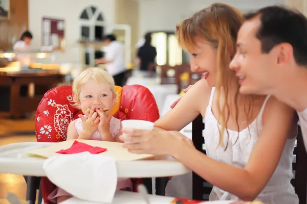 Happy family with blond little girl eating bread