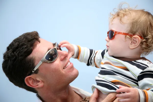 Father with the child in the sunglasses against the background of the sky