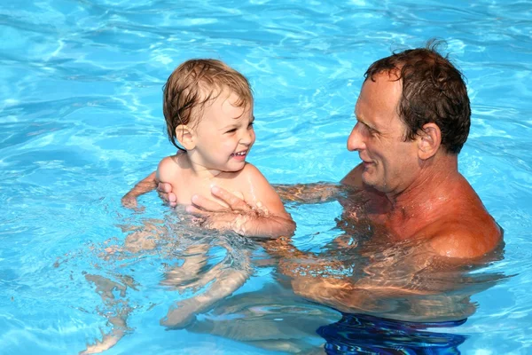 Grandfather and grandchild playing together in the pool. Outdoor, summer.