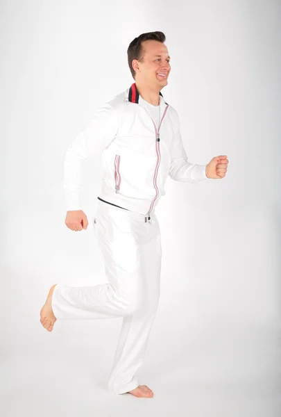 Man in white sports suit runs barefoot