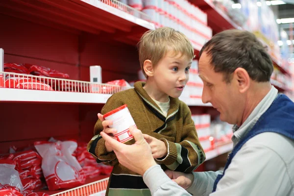 Grandfather and grandson choose conserve in food shop