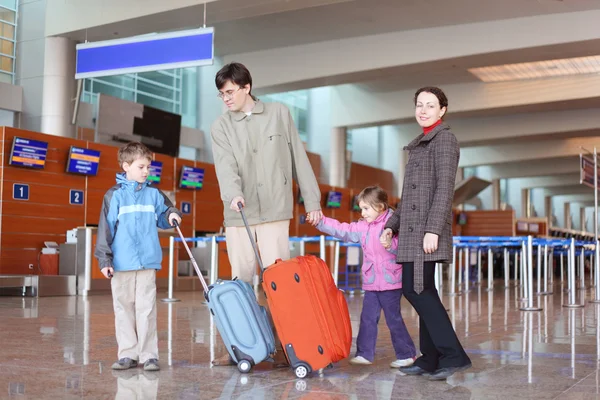 Family with suitcases walking in airport hall