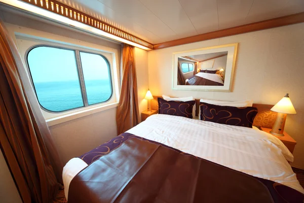 Ship cabin with big double bed and window with view on sea summe