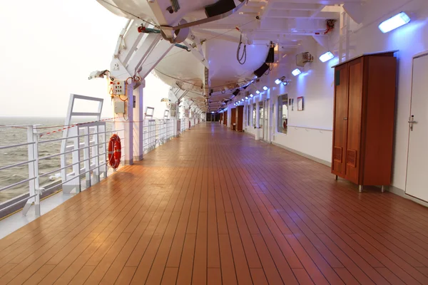 Cruise ship deck with wooden brown floor and turned on lamps at