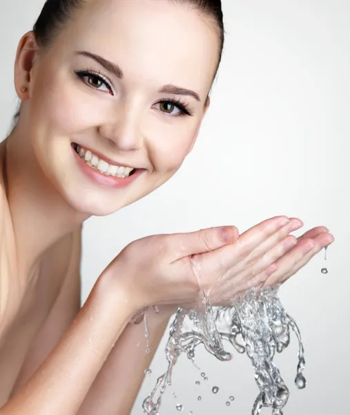 Smiling woman washing face with water