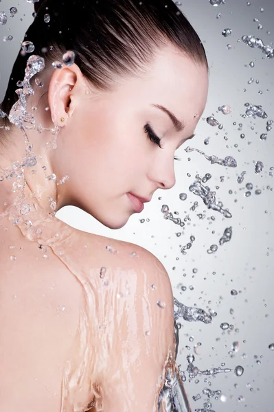 Splashes and drops of water around the female face