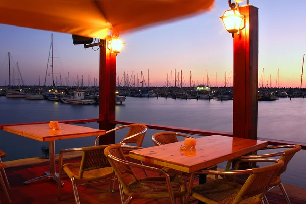 Outdoor restaurant on marina at evening.