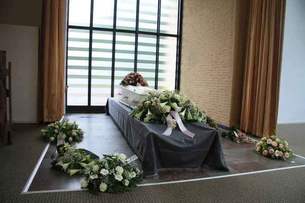 White coffin with sympathy flowers