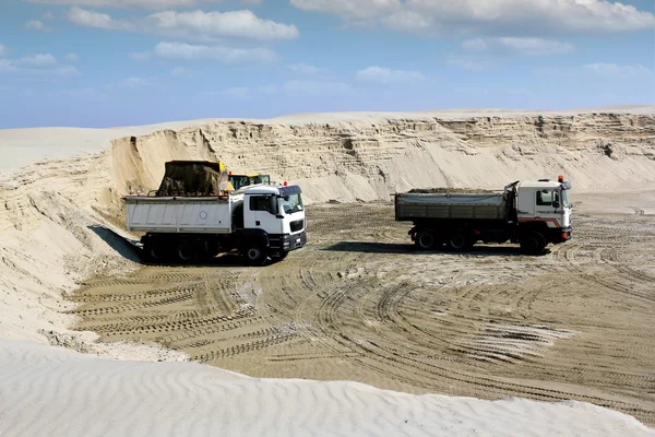 Bulldozer loading truck with sand