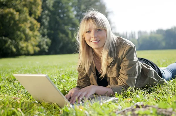 Young woman with laptop on a meadow