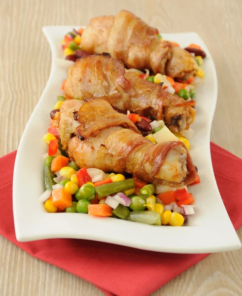 Chicken leg wrapped in bacon with vegetables