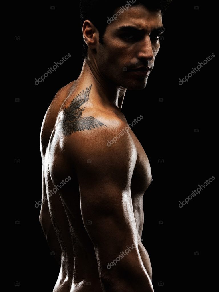Portrait of a muscular fashion man with tattoo on his back giving you a 