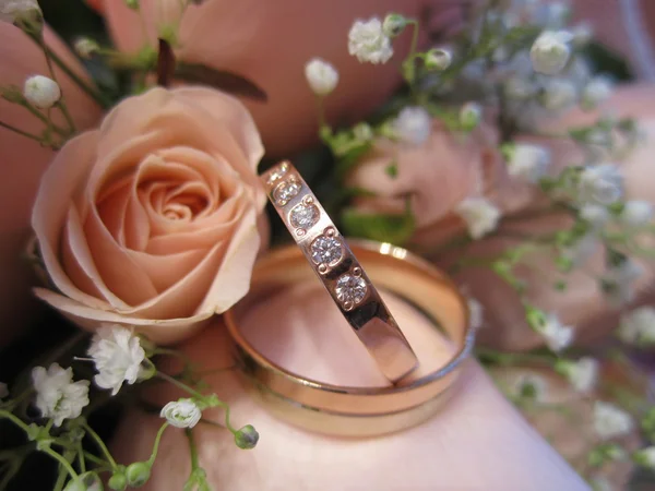 Wedding gold rings lie on a bunch of flowers for the bride by Aleksey 