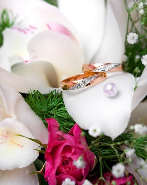 Wedding gold rings lie on a bunch of flowers for the bride by Aleksey
