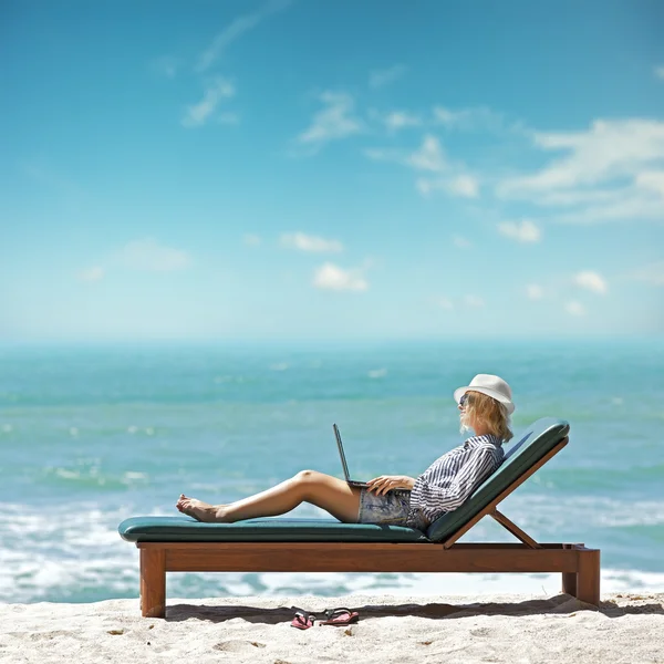 Young woman with laptop at the beach