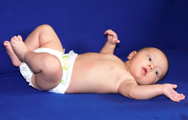 Beautiful happy baby girl lying on the back and looking on blue