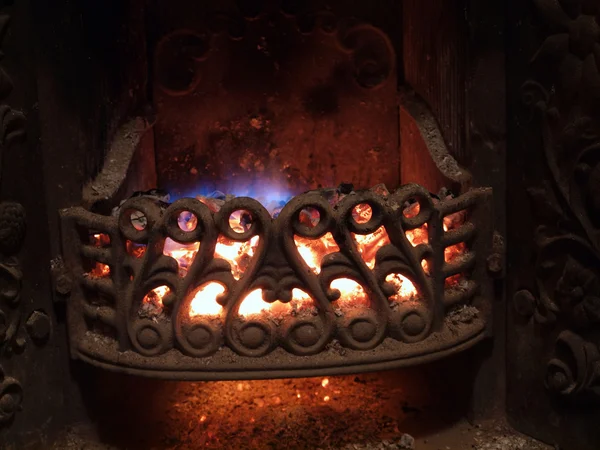 Old cast-iron fireplace with glowing coals