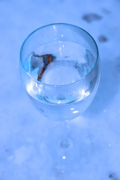 Glass of cool water in crisp snow
