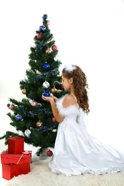 Little beautiful girl near a christmas tree isolated on a white background