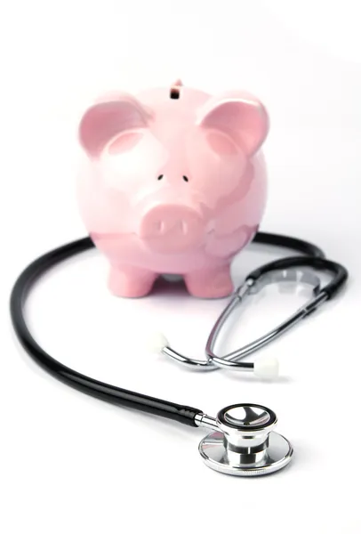 Piggy bank and stethoscope on white