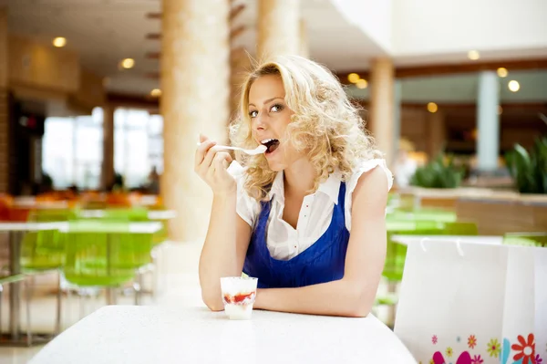 Young woman enjoying coffee time at mall cafe. Eating ice cream