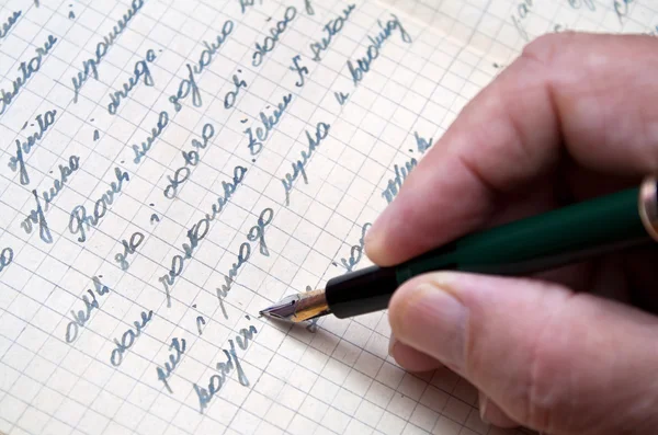 Hand with pen writes letter.