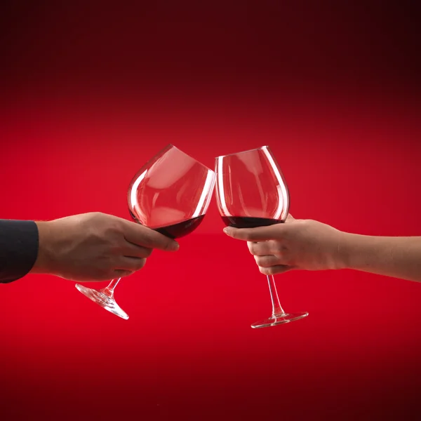 Couple holding glasses of red wine toasting