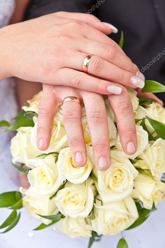 Hands with wedding rings on a wedding bouquet