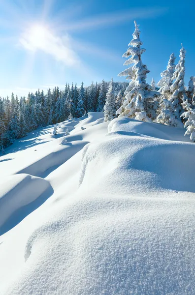 Snowdrifts on winter snow covered mountainside and sun
