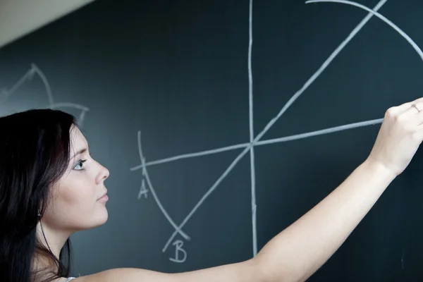 Pretty young teacher drawing on the chalkboard/blackboard