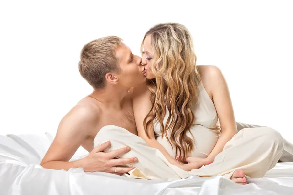 Young couple in bed wait for baby kiss together