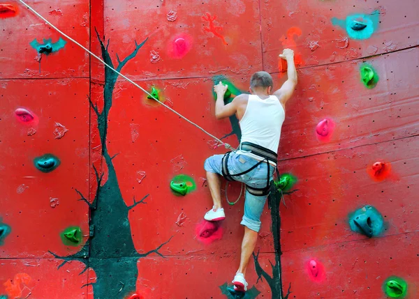 Strong man climbing on a climbing wall