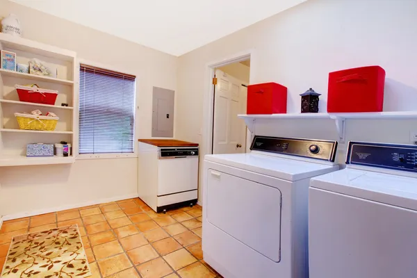 Laundry room with window and ceramic tile floor in a village hou