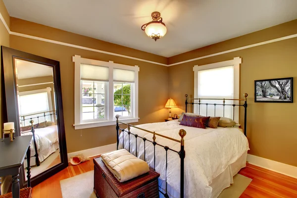 Bedroom interior with golden walls and oak floor.