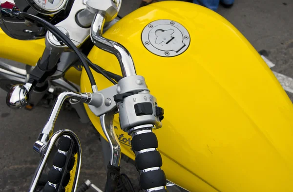 Motorcycle wheel and yellow petrol tank details.