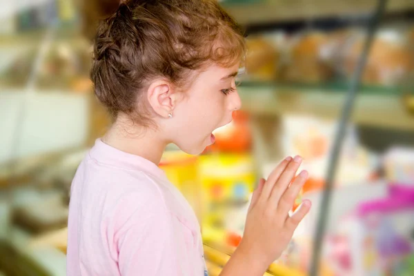 Child little girl looking in food shop display