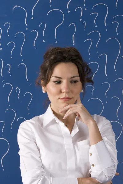 Thinking business woman in front of question marks