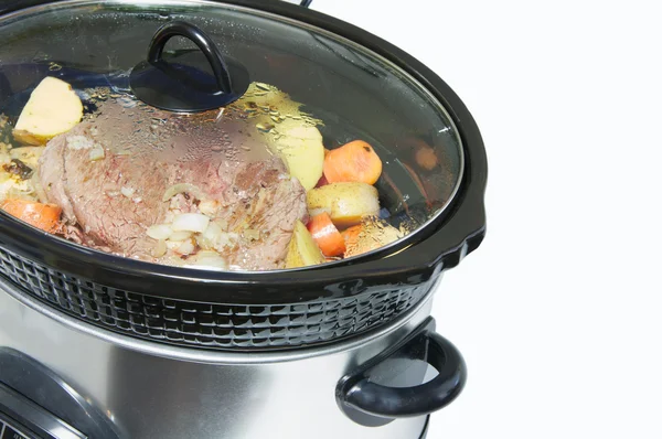 Close up slow cooker with roast beef and vegetables.