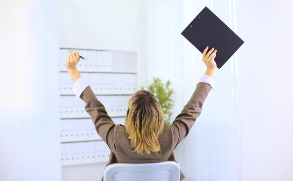 Woman sitting in a chair and with her hands in the air celebrating success