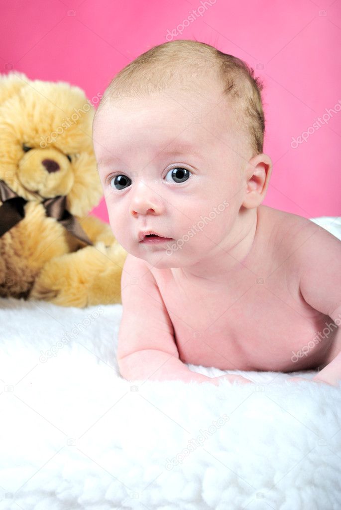 The little boy with the big eyes naked a pink background with a bear