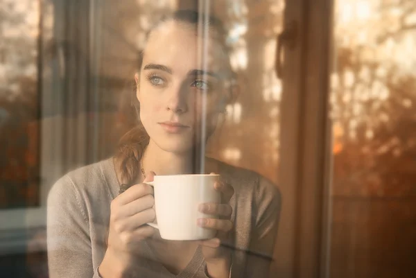 Beautiful woman drinking coffee in the morning sitting by the window