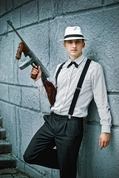 Young guy in a hat and a suit holding rifle