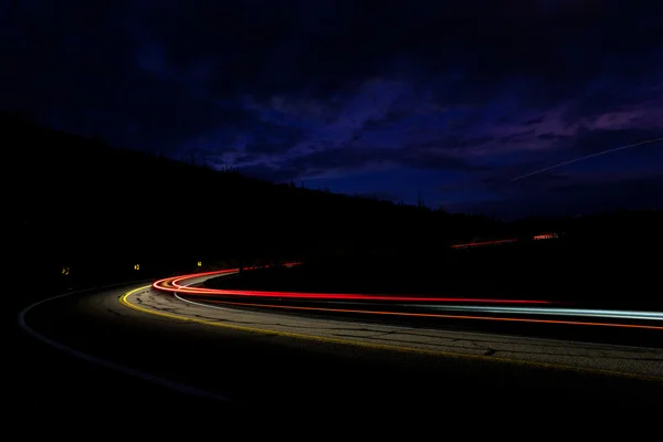 Light of cars speeding in the night through dence curves in the
